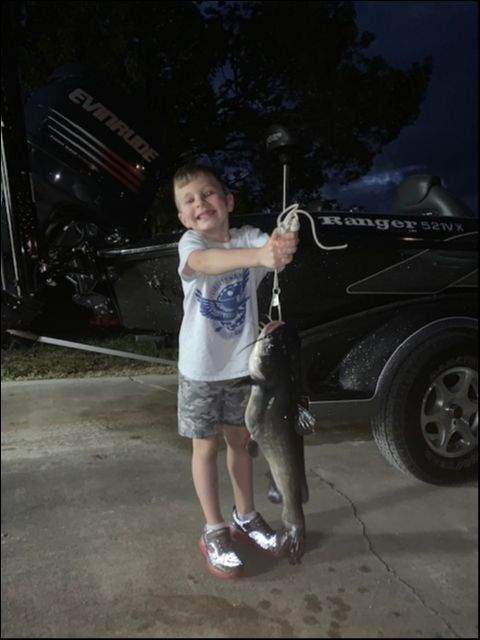 A boy struggling to lift his prized catfish